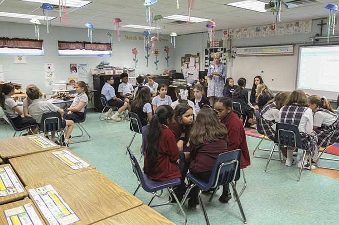 Queen of Angels librarian Sue Van Rooyen, standing in the background, presented book questions to the fifth-grade teams during the semifinal round. Each grade level, third through eighth, subdivided by an “A” and “B” team, competed in their respective rooms to determine which 12 teams would compete in the Battle of the Books finals. Photo By Michael Alexander