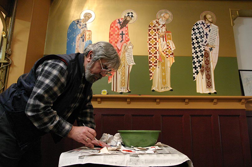 Mixing cadmium red with burnt sienna, Father Dimitri Leussis comes up with the color for the lettering that will accompany the new icons at St. John Chrysostom Melkite Church, Atlanta. Photo By Michael Alexander