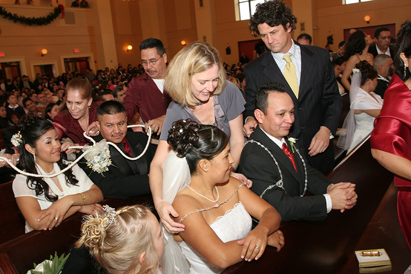 Jane and Bill Pritchard, standing center, place the lazo (lasso) around the shoulders of Angela and Mariano Perez of Chattanooga, Tenn. The large rosary symbolizes the marital union of the couple. Photo By Michael Alexander