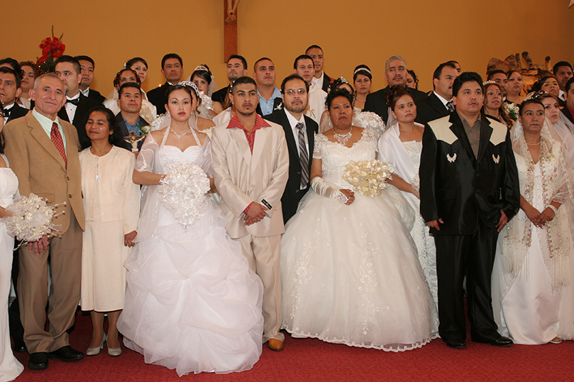 Father Jesús-David Trujillo stands among the 31 couples as their families take a group photograph. Photo By Michael Alexander