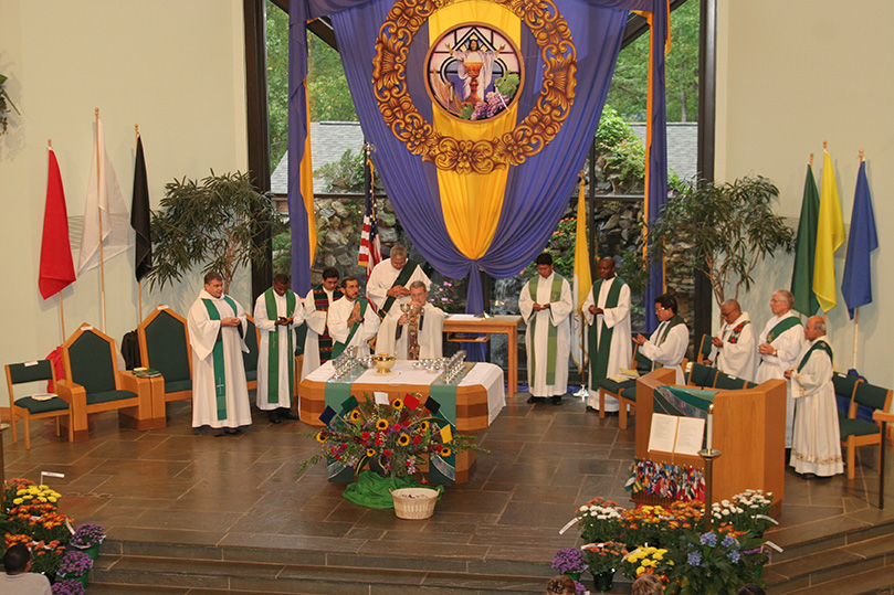 Father Gregory Hartmayer, pastor of St. Philip Benizi Church, Jonesboro, standing at the altar, is joined by his brother clergy in the sanctuary during the Liturgy of  the Eucharist. Photo By Michael Alexander