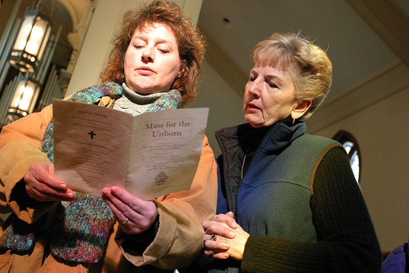 Diana Shepherd, left, of Saint Marguerite d'Youville Church, Lawrenceville, and Rosemary Risse of St. Joseph Church, Athens, stand before the congregation as they join a host of others commissioned as Pro-Life representatives for their parishes.  Photo By Michael Alexander