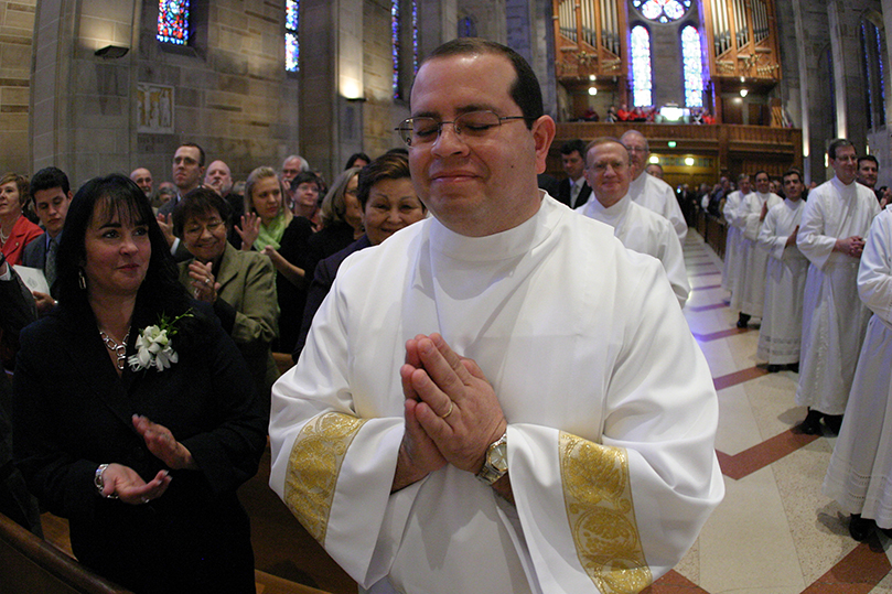 At the “calling of the candidates” Miguel Echevarria of St. Catherine of Sienna Church, Kennesaw, joins his fellow deacon candidates in the center aisle of the Cathedral of Christ the King, Atlanta during the Feb. 7 diaconate ordination as his wife Maria, left, looks on. Photo By Michael Alexander