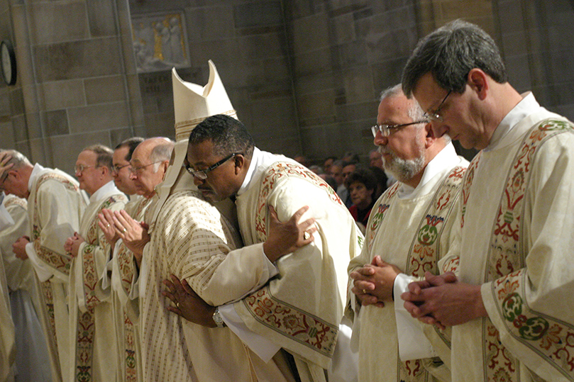 Six-foot-two-inch Deacon King Cooper Sr. leans over to greet Archbishop Gregory during the Kiss of Peace. Cooper is assigned to St. Matthew Church, Tyrone. Photo By Michael Alexander