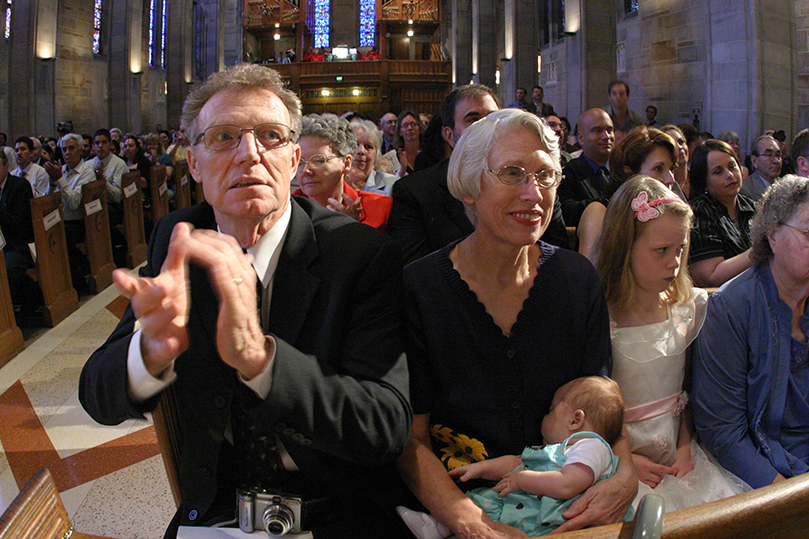 Sitting next to his wife Becky, John Gallagher applauds as his son Tim and the other seven ordination candidates are presented to the congregation. Photo By Michael Alexander