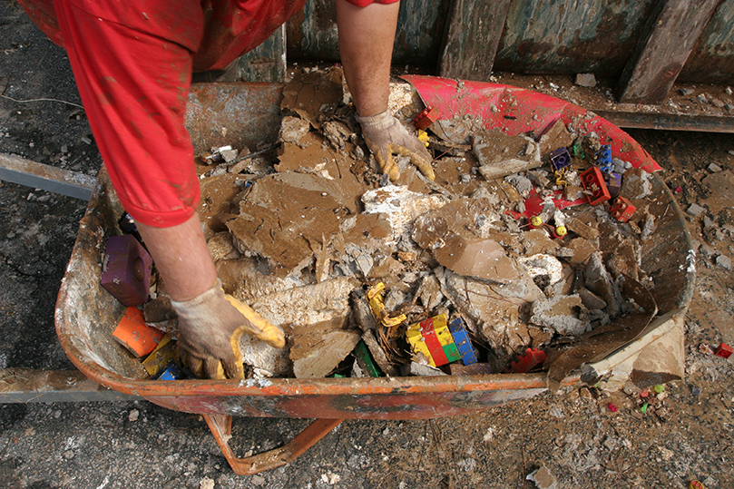 Msgr. David Talley, pastor of St. John Neumann Church, prepares to place the trash and debris pulled from the parish preschool into the dumpster on the premises.