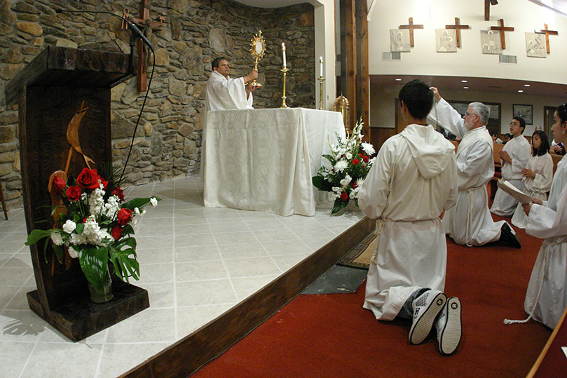 Father Victor Reyes, pastor of Our Lady of LaSalette Church, Canton, elevates the monstrance containing the Blessed Sacrament during a Sept. 15 liturgy of evening praise. Photo By Michael Alexander