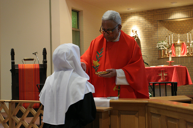 Missionary of St. Frances de Sales Father Joseph Mendes distributes the body of Christ to a sister during morning Mass at the Monastery of the Visitation. Father Mendes serves as the monastery's chaplain. Photo By Michael Alexander