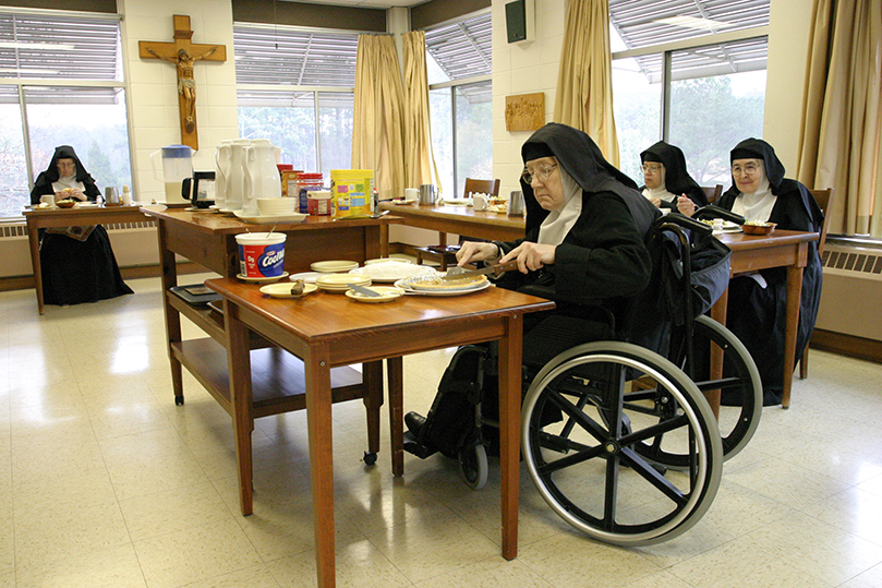 Sister Mary Regina, foreground, cuts a slice of pumpkin pie as the community gathers in the refectory for lunch in silence. Photo By Michael Alexander