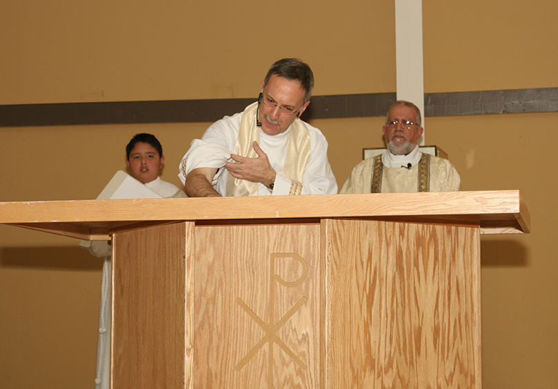 During the rite of dedication Bishop Zarama rubs down the altar with holy oil as an altar server and Deacon José G. Espinosa León, right, look on. Photo By Michael Alexander