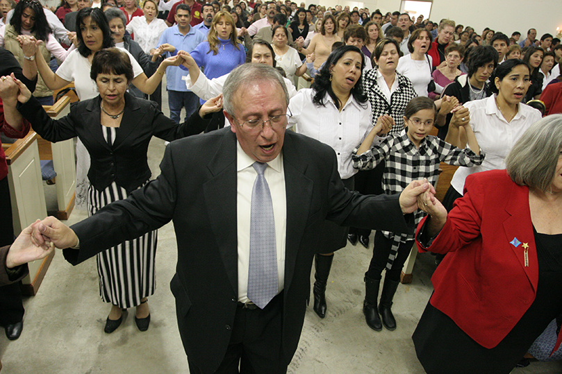 Rafael Gaitan, center, joins hands with others as they pray the Our Father together at the new Divino Niño Jesus Mission. Photo By Michael Alexander