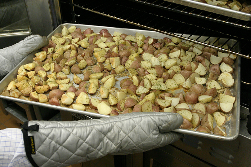 David Webster removes the potatoes from the oven. Photo By Michael Alexander