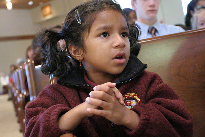 Kindergartener Annie Abraham joins the congregation in singing the responsorial from Psalm 103. The regional Catholic school celebrated its 25th anniversary during a special Mass Oct. 14. Photo By Michael Alexander