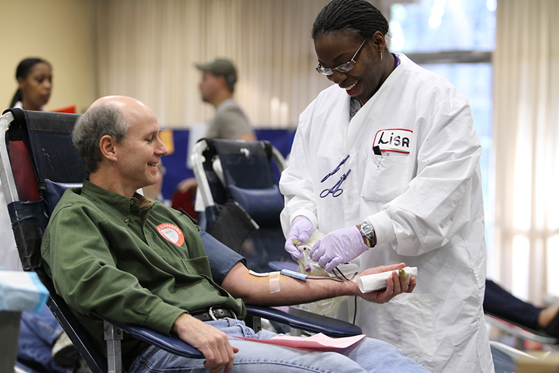 Kevin Melvin gets assistance from American Red Cross blood collection technician Melissa Gay as he completes his donation process. Melvin was one of 190 people who showed up to donate during the Dec. 11 blood drive at Holy Cross Church, Atlanta. Photo By Michael Alexander