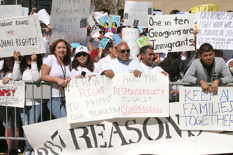 (Starting third from the left) Esmeralda Orozco, Nora Soto and Miguel Orozco of Our Lady of the Americas Mission, Lilburn, hold their sign among the thousands of protestors on hand voicing their opposition to House Bill 87 and Senate Bill 40. The March 24 immigration rally took place in front of the Georgia State Capitol. Photo By Michael Alexander