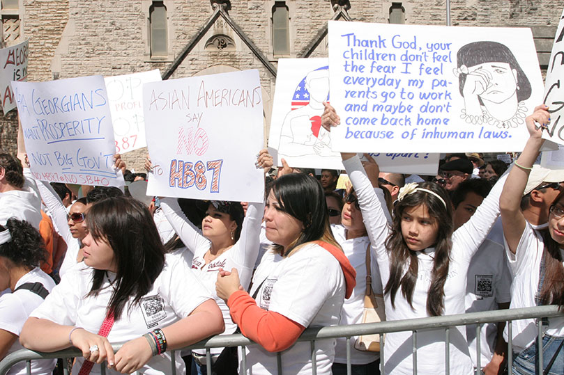 Eleven-year-old Stephanie Hernandez of Dunwoody, second from right, holds a sign above her head during the immigration rally that started in the morning, but went a couple hours beyond noon. Photo By Michael Alexander