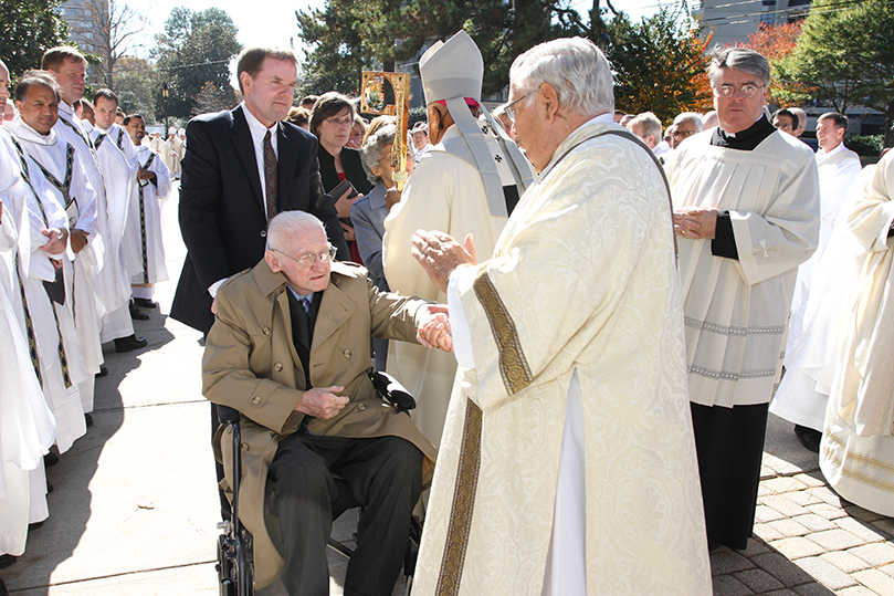 Deacon Ray Egan, foreground, right center, extends a word of sympathy to Edward Donoghue, the 81-year-old brother of Archbishop John F. Donoghue, while Archbishop Gregory, background center, expresses his condolences to the rest of the family. Photo By Michael Alexander