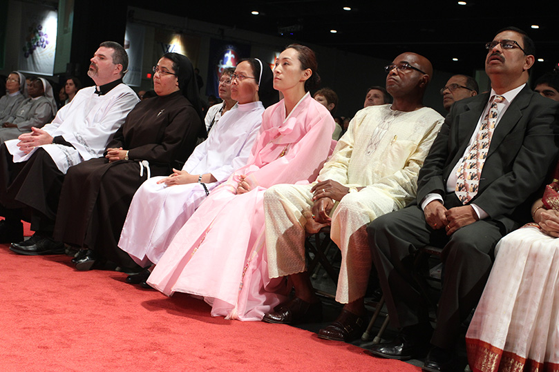 Deacon Thomas McGivney of St. Thomas Aquinas Church, Alpharetta, far left, the master of ceremonies for the closing Mass, sits with the readers of the word and the general intercessory prayer readers of different cultures. Photo By Michael Alexander