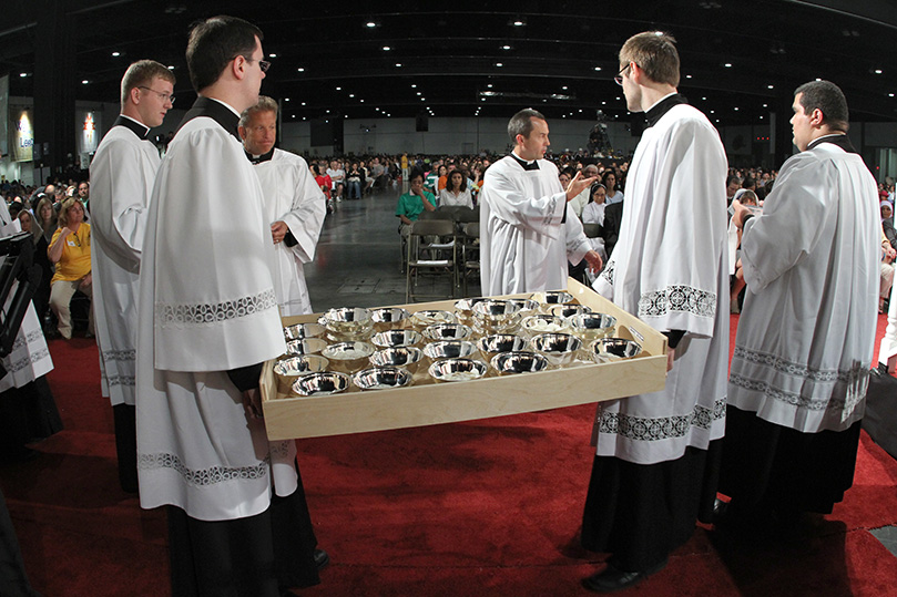 Father Thomas Zahuta, third from right, parochial vicar at Saint Monica Church, Duluth, helps clear a path for the seminarians so they can return the extra communion hosts to the rear of the altar. Photo By Michael Alexander