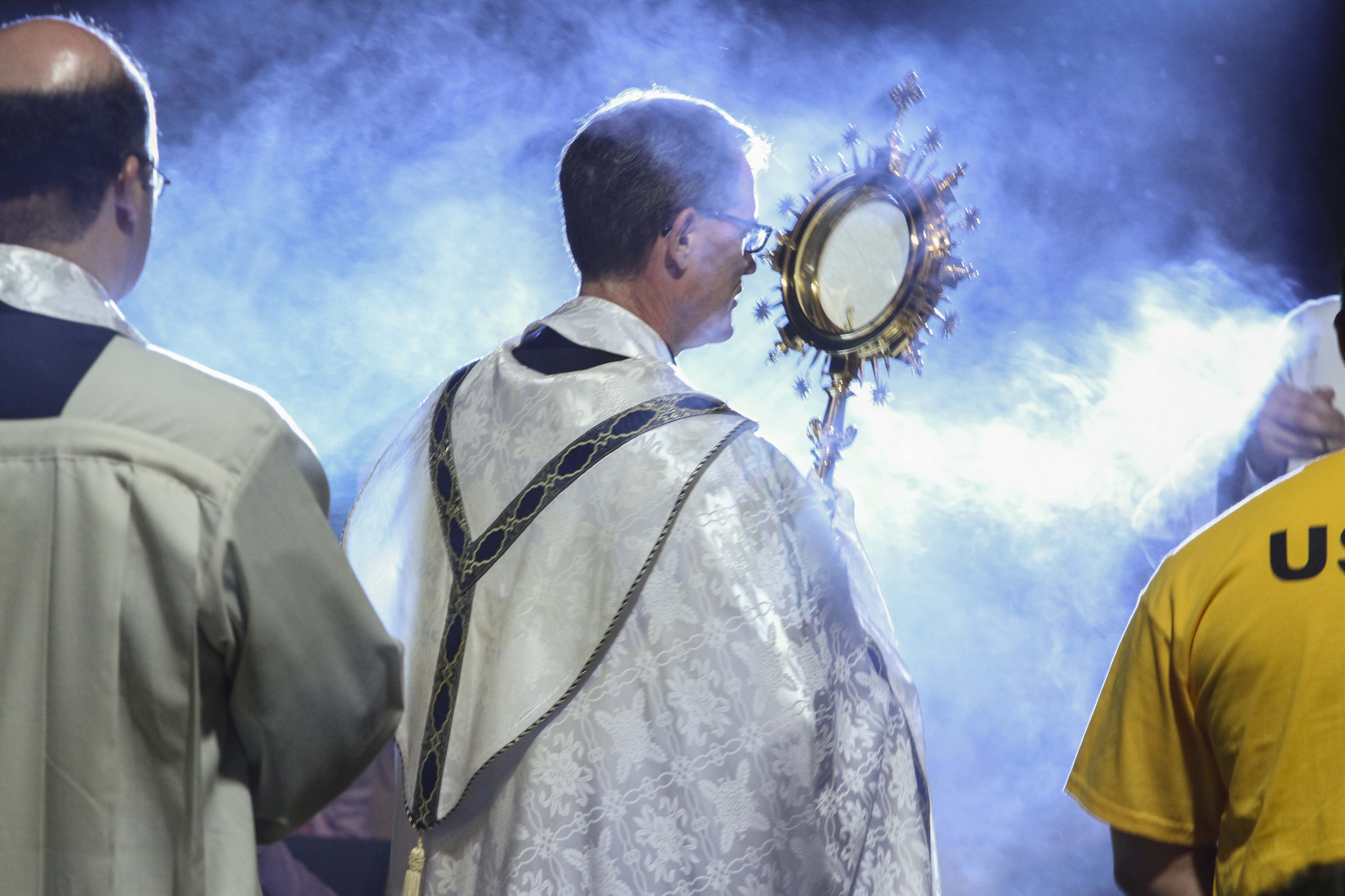 Father Jack Durkin, pastor of St. Monica Church, Duluth, processes around convention hall carrying the monstrance holding the precious body of Christ. Photo By Michael Alexander