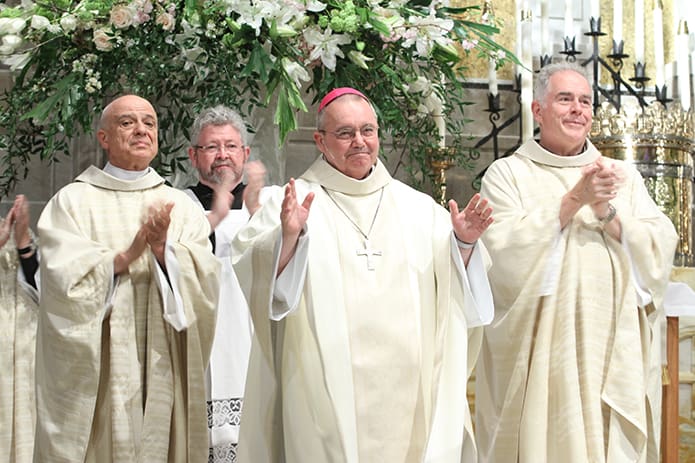 The congregation and his brother clergy applaud following the reading of the Apostolic Letter from the Holy Father. Photo By Michael Alexander