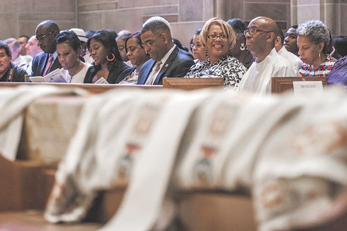 Desmond Drummer, second from right, sits with his family and friends as the ordination Mass begins.