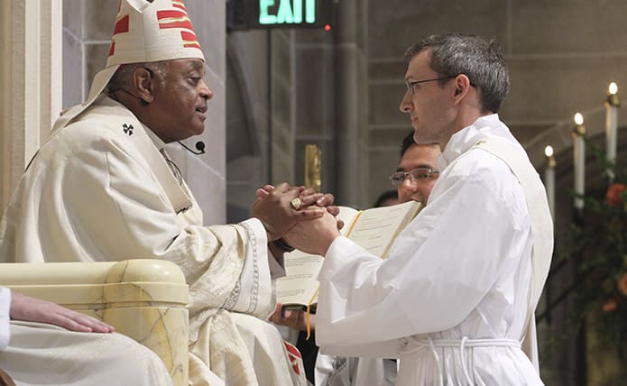 Matthew Dalrymple, right, makes a promise of obedience to Archbishop Wilton D. Gregory, left, and his successors. Photo By Michael Alexander