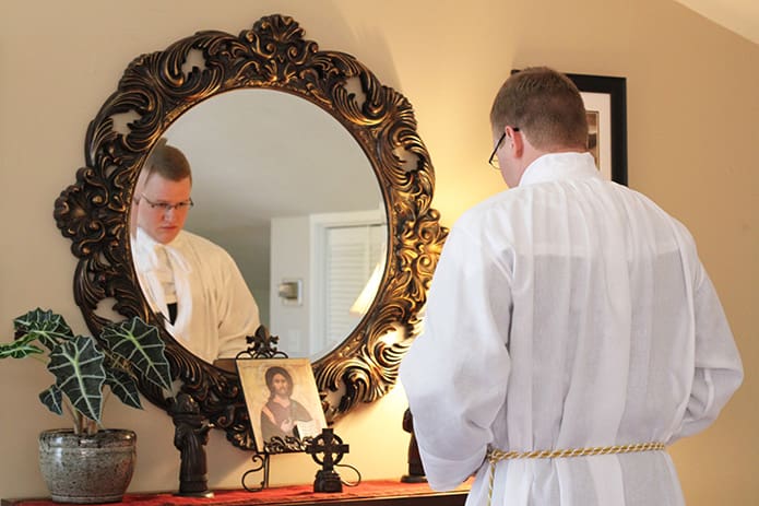 About 40 minutes before his transitional diaconate ordination, Tim Nadolski gets ready as he adjusts the cincture around his alb in the rectory at the Cathedral of Christ the King, Atlanta. Photo By Michael Alexander