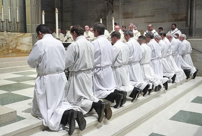 The candidates kneel on the steps of the altar during the Feb. 7 rite of ordination to the diaconate as Archbishop Gregory conducts the prayer of consecration. Photo By Michael Alexander