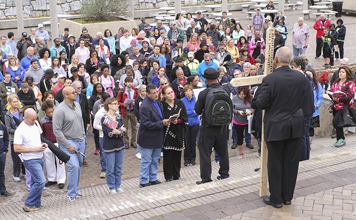 Archbishop Wilton D. Gregory holds the cross in the foreground and participants listen to a reflection based on the theme of homelessness for the second Station of the Cross (Jesus takes up his cross) at Talmadge Park. Photo By Michael Alexander