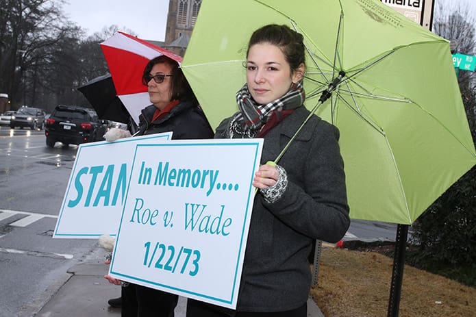 Smyrna resident Audra Pagano, foreground, holds a sign under rainy skies during Stand for Life, Jan. 22, at the intersection of Peachtree Road and West Wesley Road. Photo By Michael Alexander