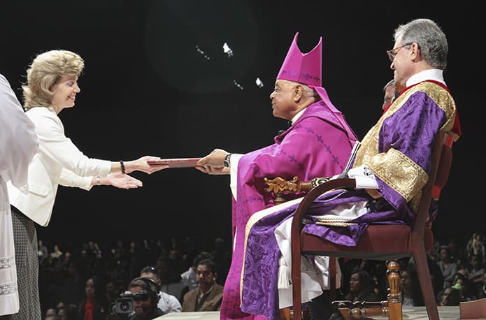 Barbara Conticelli, left, assistant adult education coordinator at St. Brigid Church, Johns Creek, presents the Book of the Elect to Archbishop Wilton D. Gregory during the Feb.14 Rite of Election and the Call to Continuing Conversion at the Cobb Galleria Centre, Atlanta. The North Fulton County parish has 13 catechumens and 37 candidates. Photo by Michael Alexander