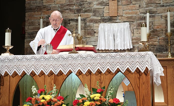 Deacon Evelio Garcia-Carreras prepares the altar for the Liturgy of the Eucharist during 9 a.m. Mass at St. Stephen the Martyr Church in Lilburn. Photo By Michael Alexander