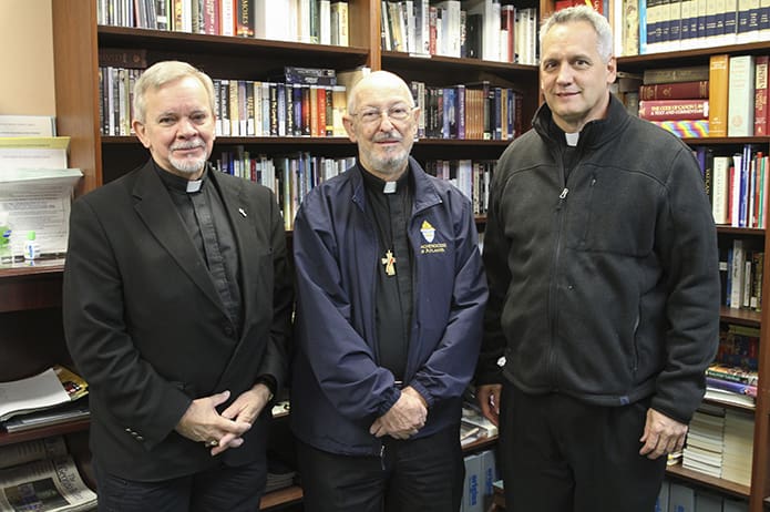 After Mass Deacon Evelio Garcia-Carreras, center, poses for a photograph with Father Brian Lorei, right, pastor of St. Stephen the Martyr Church, Lilburn, and fellow deacon Mike Mobley. Deacon Evelio Garcia-Carreras has been a deacon for 31 years and Deacon Mobley has been a deacon for 24 years. Photo By Michael Alexander