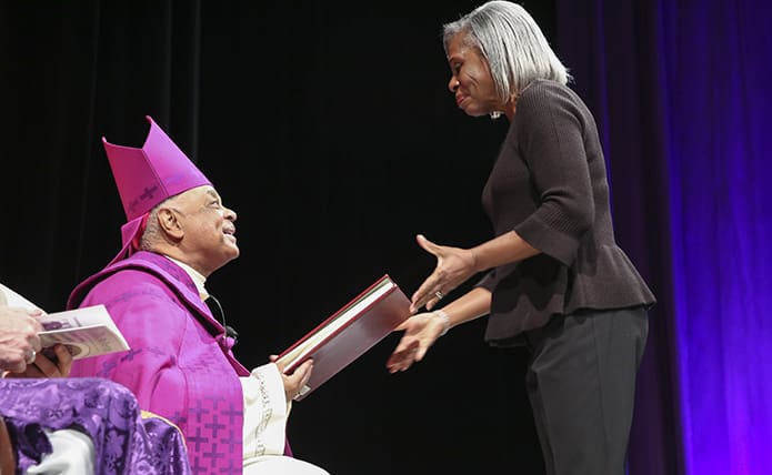 Archbishop Wilton D. Gregory returns the Book of the Elect to Pat Davis, of Sts. Peter and Paul Church, Decatur. The Archdiocese of Atlanta had 1,988 candidates and catechumens attend the 2018 Rite of Election and the Call to Continuing Conversion. Photo By Michael Alexander