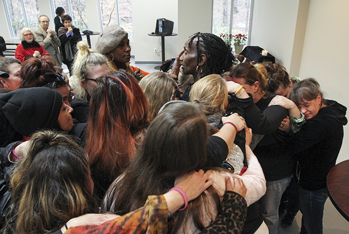 Overcome with emotion as she talks about Mary Hall Freedom House (MHFH) and its mission for the past 22 years, Lucy Hall, right center, the founder and CEO, wipes away her tears, as the many women who benefit from MHFHâs services immediately come up to surround and embrace Hall in a show of solidarity. Photo By Michael Alexander