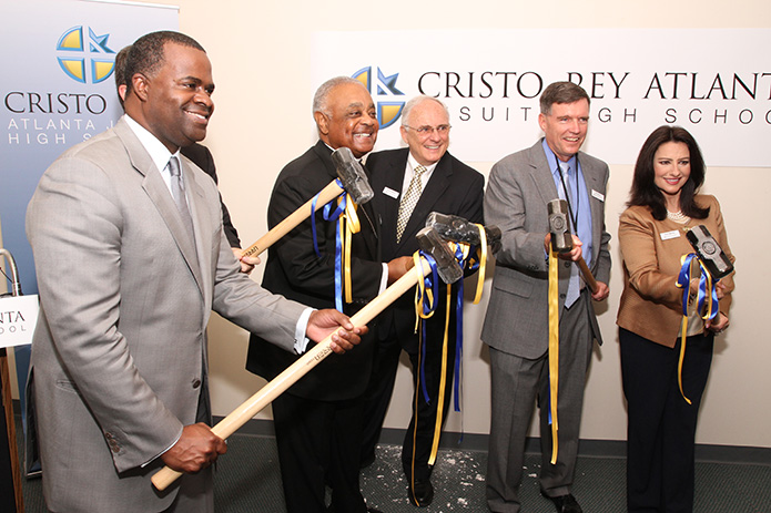 In September 2013 (l-r) Kasim Reed, Mayor of Atlanta, Archbishop Wilton D. Gregory, Bob Fitzgerald, Cristo Rey Atlanta board chair, Bill Garrett, president of Cristo Rey Atlanta, and Ileana Martinez, Cristo Rey Atlanta board member, pose for a photo holding sledgehammers. The groundbreaking at the former Archdiocese of Atlanta Chancery took the form of wall busting to symbolize the new renovations that would take place at the initial site of Cristo Rey Atlanta Jesuit High School. Photo By Michael Alexander  