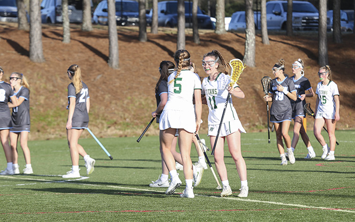 After an assist from Blessed Trinity midfielder Kaley Attaway (#5), and a subsequent goal by fellow midfielder Kelly Scott (#11), her fourth of four first-half goals, the two salute one another. Scott, the team’s second leading scorer behind Attaway, finished the match with six goals, but Blessed Trinity suffered its first defeat of the season, a 17-13 loss to Milton’s Cambridge High School. Photo By Michael Alexander