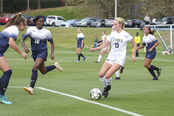 Marist School defensive back Eva Wirtz, left, and midfielder Annika Bryant (#18) give chase to St. Pius X forward Renee Lyles (#10), who scored one of the goals in St. Pius’ 2-0 victory over Marist. Photo By Michael Alexander