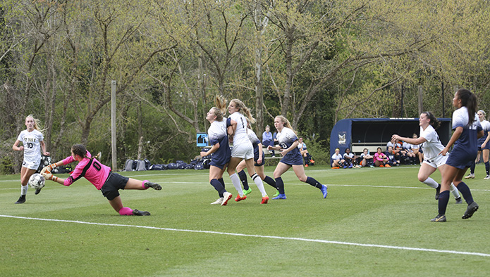 With 18:54 left in the first half, St. Pius X forward Renee Lyles (#10) gets the ball by the outstretched hands of Marist School goalie Eva Nahas (#0) for the second and final goal in St. Pius’ 2-0 victory over Marist in their March 29 regular season meeting. Both teams went scoreless in the second half. Photo By Michael Alexander