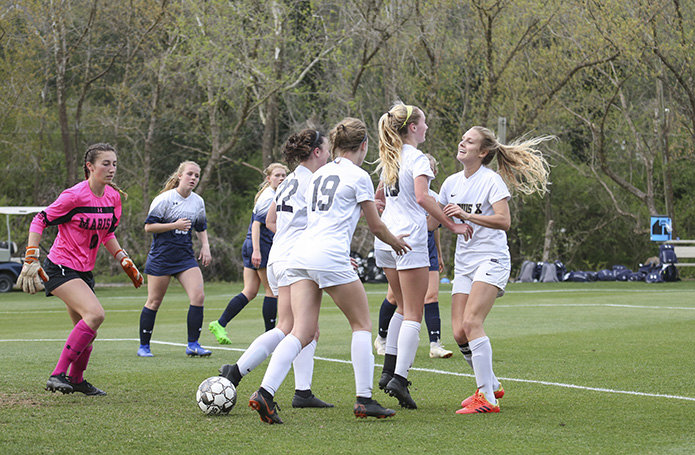 St. Pius X forward Renee Lyles, second from right, celebrates with her teammates, Helen Cherry, far right, Caroline Shea (#22) and Lauren Bynum (#19) after scoring the second and final goal in St. Pius’ 2-0 victory over Marist in their March 29 regular season meeting. Photo By Michael Alexander