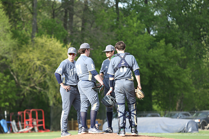 St. Pius X assistant coach Andrew Mabini, second from right, takes a walk to the mound to speak with starting pitcher Matthew Burdick (#28). Listening in are first baseman Nick Kosek, left, and catcher Nicolas Robinson, right. Mabini works with the pitchers and middle infielders in his role as coach. Photo By Michael Alexander