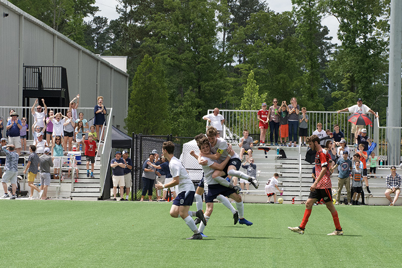 St. John Bosco Academy's Jackson Wearne jumps into the arms of JP Whelan after Whelan scored the go-ahead goal during the May 4 Georgia Independent Christian Athletic Association (GICAA) Division II-AA state championship game. St. John Bosco would go on to win its first state championship 3-2. Photo Courtesy of St. John Bosco Academy