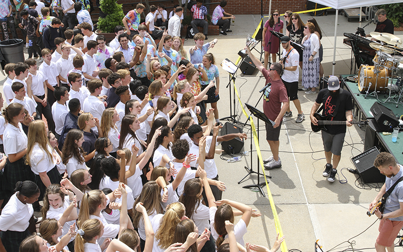 During the May 1 Teacher Jam, St. Pius X High School social studies teacher and head swimming and diving coach Scott Carter holds the boys’ 2019 swimming and diving state championship trophy as he leads the band in a rendition of Queen’s “We Are The Champions.” They did a medley of Queen songs that also included “Crazy Little Thing,” “Tie Your Mother Down” and “We Will Rock You.” Photo By Michael Alexander