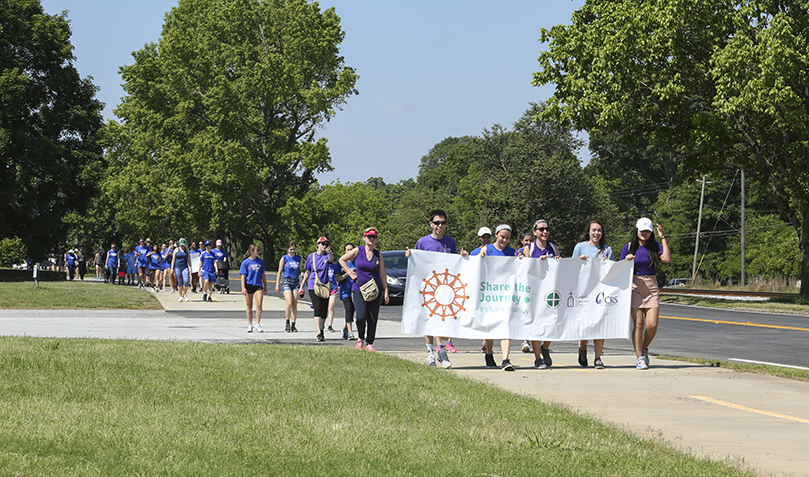 Carrying the Share the Journey banner during mile three of five are (l-r) Jimmy Lai, Emma Dunphy, Adrian Laudani, Emily Longino and Grace Lin. All four serve in some capacity at Catholic Charities Atlanta. Lai and Lin are AmeriCorps volunteers with Refugee Services. Dunphy is a paralegal with Immigration Legal Services. Laudani is a Jesuit volunteer working as a refugee resettlement specialist. Longino is a volunteer. Photo By Michael Alexander