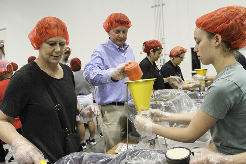 (Clockwise, from right) Grace Gant, her mother Melba and her father Toby of Good Shepherd Church, Cumming, made up a family team of meal packers. Not seen, but pouring rice in the meal bags is her twin brother Jake. Toby, a United States Navy veteran, has joined his family for all four years of Starve Wars. Photo By Michael Alexander