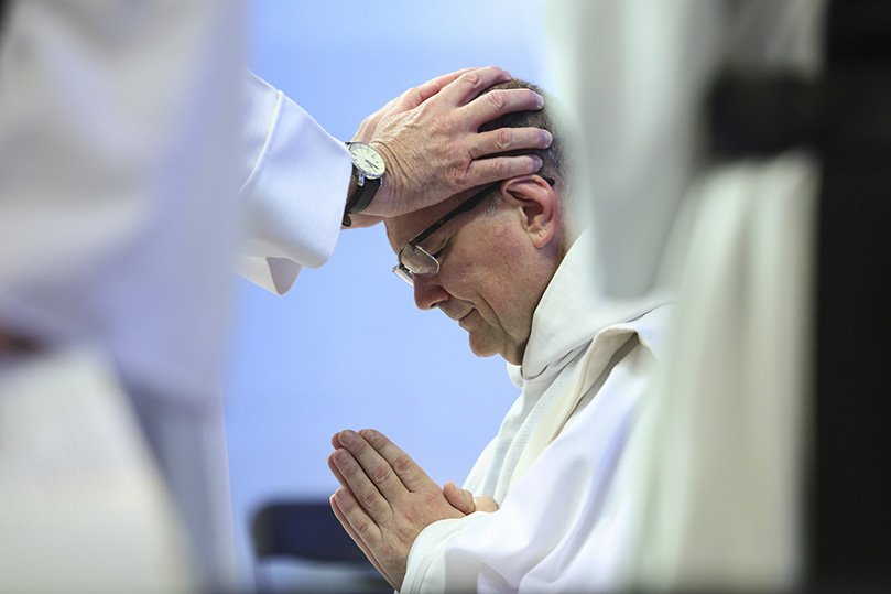 Prior to the prayer of ordination, one by one the priests in attendance lay hands on each ordination candidate, starting with Brother Peter Damian, OCSO. Photo By Michael Alexander