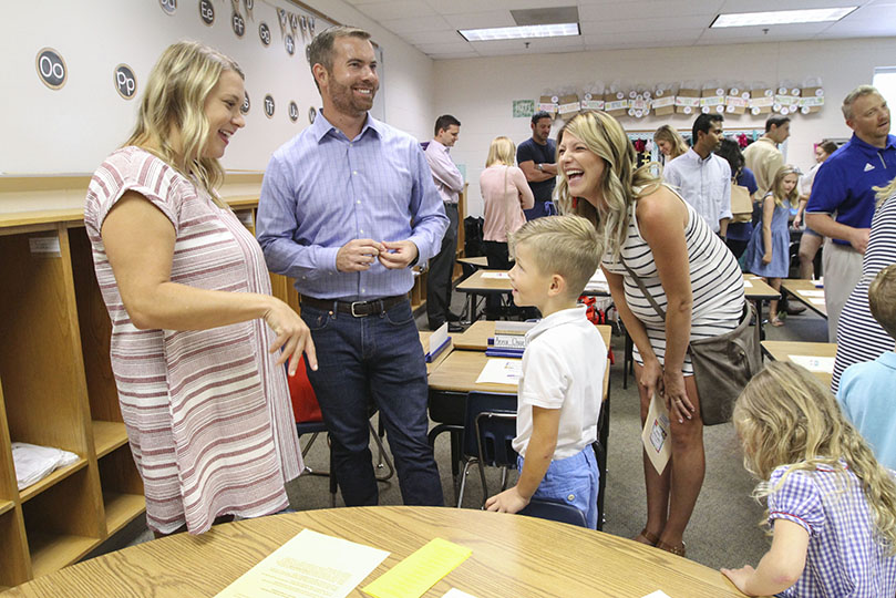 During Holy Redeemer Schoolâs August 5 meet and greet, kindergarten teacher Jessica Verar, left, shares a humorous moment with six-year-old Logan Wise, a new student at the Johns Creek Catholic school. Looking on are his parents James and Jessica. Photo By Michael Alexander