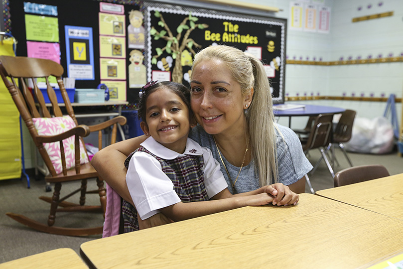 Elvira Mujkic hugs her daughter, Ashley Sanchez-Mujkic, on the first day of school in Ashley's first grade classroom at St. John Neumann Regional School, Lilburn. Photo By Michael Alexander