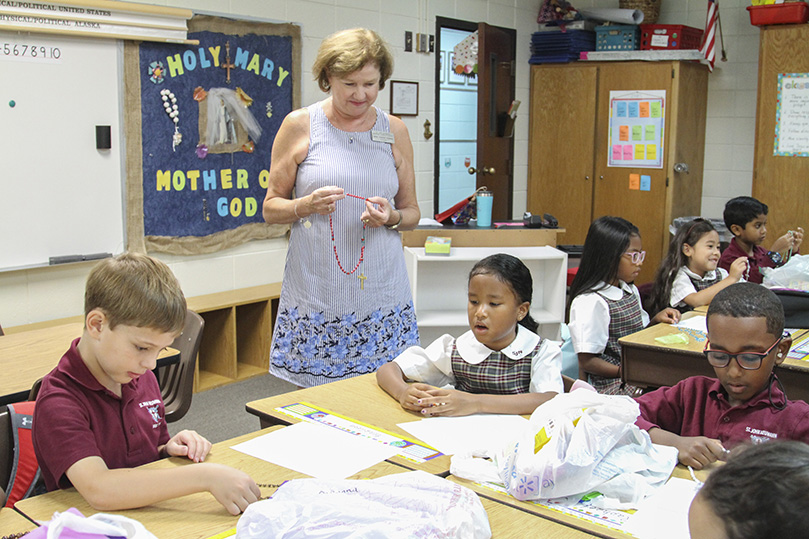 Second grade teacher Karen Hoban, standing, begins each day of class at St. John Neumann Regional School, Lilburn, by praying a decade of the rosary with her students. On August 5, the first day of school, they prayed the first joyful mystery, the Annunciation. Hoban, who is also the product of a Catholic school education, graduated from Atlantaâs Christ the King School and St. Pius X High School. Photo By Michael Alexander